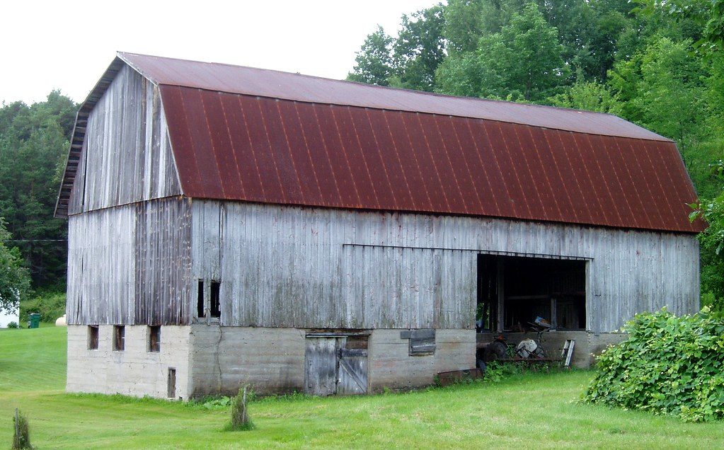 Typical condition: old corrugated tin roof with rusted panels, exposed fastener heads, and lifted seams.